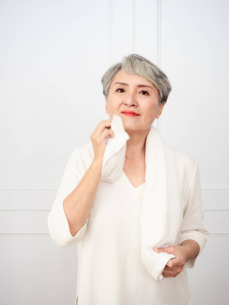 Portrait of mature aged asian woman 50s with towel at home. - Foto, immagini