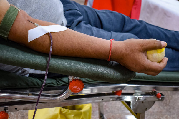 Donante de sangre en el campamento de donación de sangre celebrado con una pelota hinchable sosteniendo en la mano en el Templo Balaji, Vivek Vihar, Delhi, India, Imagen para el Día Mundial del Donante de Sangre el 14 de junio de cada año, Campamento de Donación de Sangre - Foto, imagen