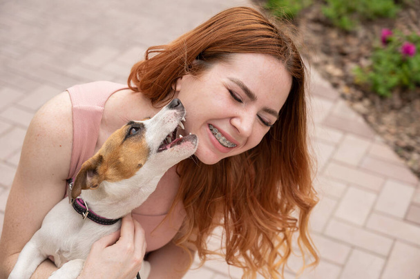 Dog jack russell terrier licks the owner in the face outdoors - Fotó, kép