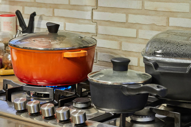 Préparation des aliments dans la poêle et les casseroles sur la cuisinière à gaz dans la cuisine. Concept de cuisine maison. - Photo, image