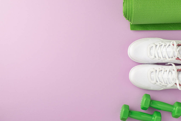 Active living concept. Top view photo of green sports mat dumbbells and white sneakers on isolated pastel violet background with empty space - 写真・画像