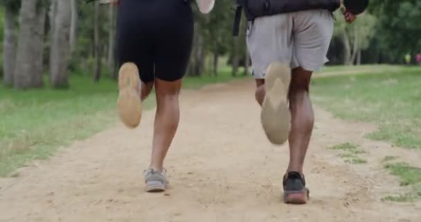 Closeup of fit couple legs running on a forest dirt road path. Active, athletic boyfriend and girlfriend bonding, training, exercising, and jogging in the woods. Man and woman in nature working out. - Video