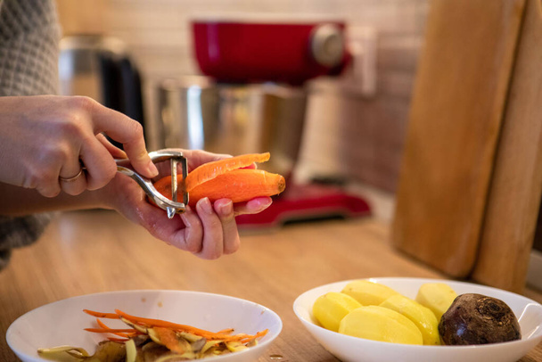 descascando cenoura close-up cooing na cozinha doméstica - Foto, Imagem