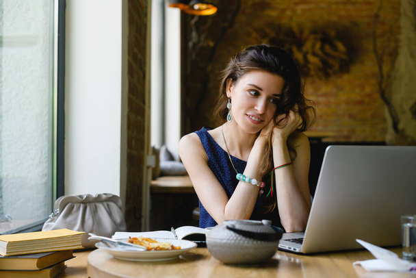 Fiatal vonzó álmodozó nő laptop kávézóban. - Fotó, kép