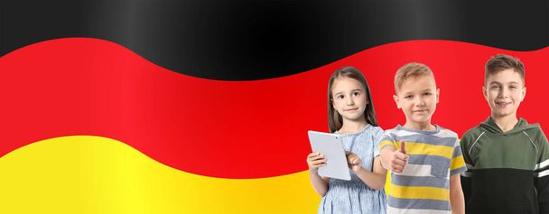 Χαριτωμένα μικρά παιδιά με tablet υπολογιστή κατά σημαία της Γερμανίας - Φωτογραφία, εικόνα