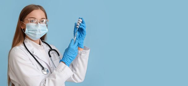 Female doctor holding monkeypox vaccine and syringe on blue background with space for text - Fotografie, Obrázek