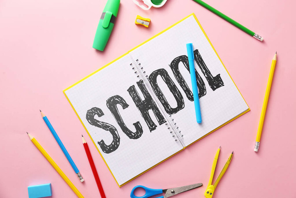 Nyitott notebook írott szó SCHOOL és írószer rózsaszín háttér - Fotó, kép