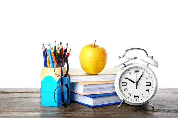 School stationery with apple, eyeglasses and alarm clock on table against white background - Zdjęcie, obraz
