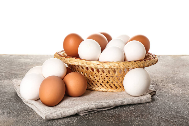 Wicker bowl with chicken eggs on table against white background - Foto, Imagem