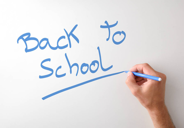 Hand writing back to school on white board with a blue marker with isolated white background - Foto, Imagem