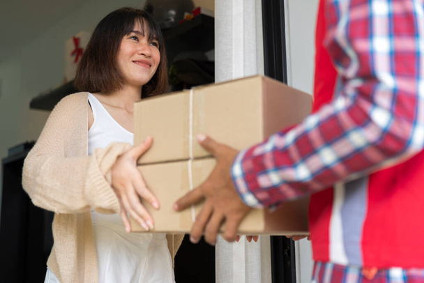 Young woman receives packages from delivery man with smiling at home. Onlines shopping concept. - Foto, imagen
