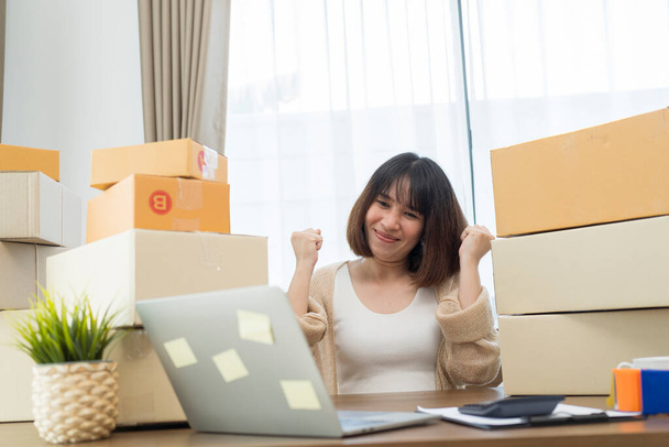 Young Women happy after new order from customer, business owner working at home office packaging on background. online shopping SME entrepreneur or freelance working concept. - Фото, изображение