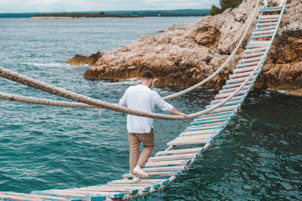 Adam asma köprü üzerinden yürüyor Yaz zamanı kopyalama alanı - Fotoğraf, Görsel