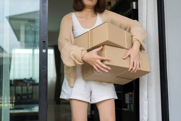 Indoor image of happy cheerful young woman holding cardboard box delivered to her, expressing excitement - Фото, зображення