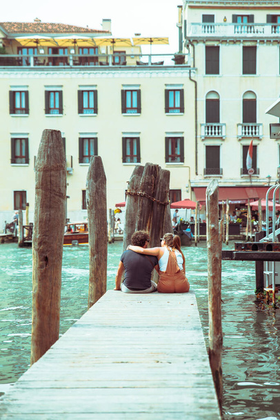 Pärchen sitzt am Pier und blickt auf große Kanal sprechende Liebhaber - Foto, Bild