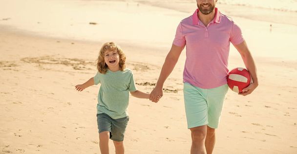Aile tatilleri. Spor aktivitesi. Kırpılmış baba ve oğul sahilde topla yürüyor. Baba ve çocuk yaz günü. Hafta sonu aile günü. Baba ve çocuk dışarıda eğleniyorlar. çocukluk ve ebeveynlik. - Fotoğraf, Görsel