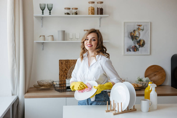 beautiful girl wipes dishes in the kitchen. High quality photo - Valokuva, kuva