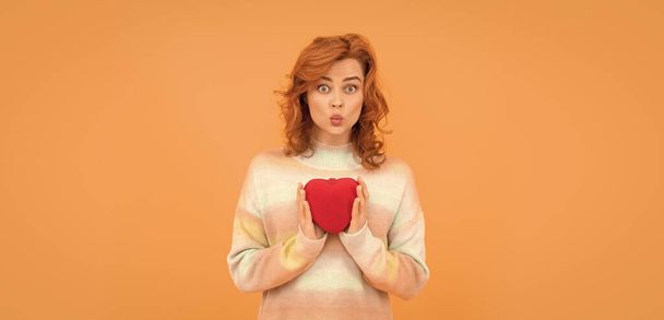 funny redhead woman with red heart on orange background. valentines. - Zdjęcie, obraz