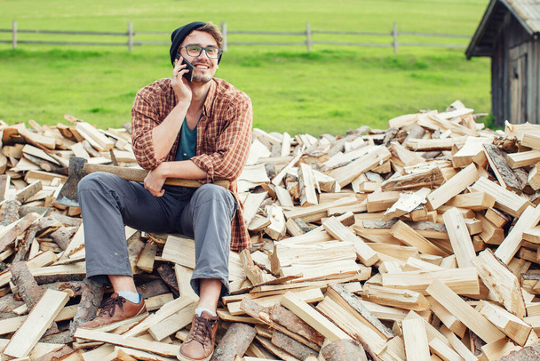 A smile on his face, a guy making a phone call attached to his ear, a cellular connection away from home, a solo hiking trip in the mountains, curly hair hipster. High quality photo - Foto, imagen