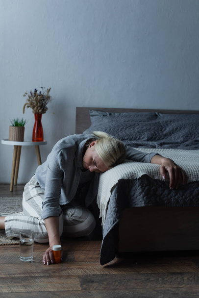 kimerült nő, akinek menopauza van, és fájdalomcsillapítókat tart a kezében, miközben szenved a fájdalomtól - Fotó, kép