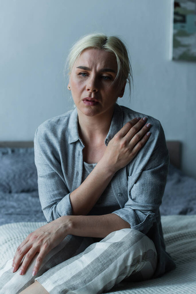 exhausted blonde woman sitting in bedroom during menopause  - Foto, Imagem