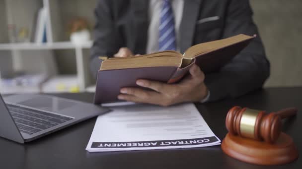 Az ügyvéd irodai jogi könyveket olvas kalapáccsal és laptoppal mellette. 4k videó. - Felvétel, videó