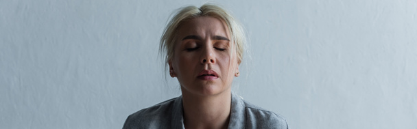 sad blonde woman with climax and closed eyes at home, banner - 写真・画像