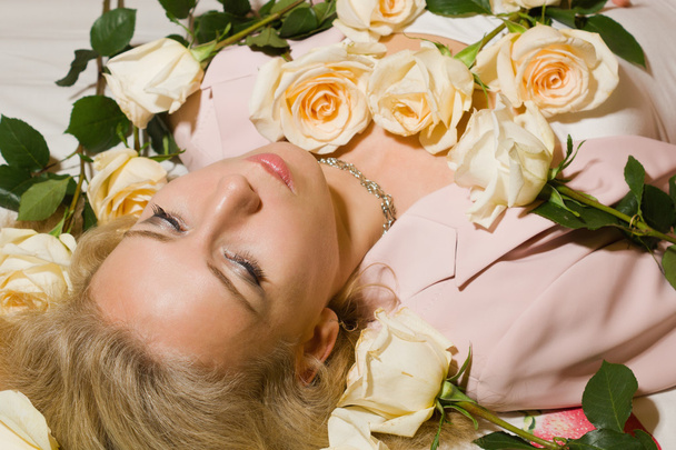 Όμορφη γυναίκα με τριαντάφυλλα, ξαπλωμένη στο κρεβάτι - Φωτογραφία, εικόνα