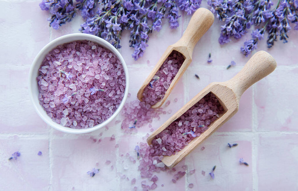 Spa products and lavender flowers on a pink tile background.  Aromatherapy lavender bath salt and massage oil - Foto, Imagen
