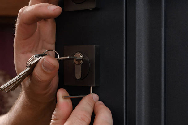 Installation of a door lock, a carpenter installs a door lock in a door, close-up work, fixing the core of the lock. - Фото, изображение