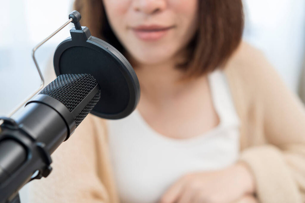 technology, mass media and people concept. Woman with microphone and headphones talking and recording podcast at studio - 写真・画像