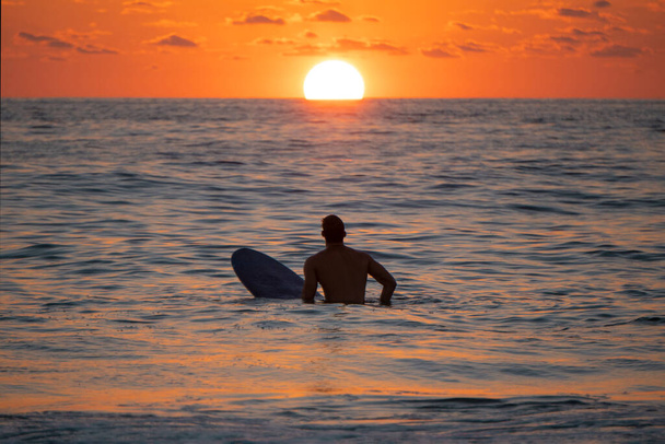 Silhouette de Surfeur en attente d'une vague au lever ou au coucher du soleil. - Photo, image