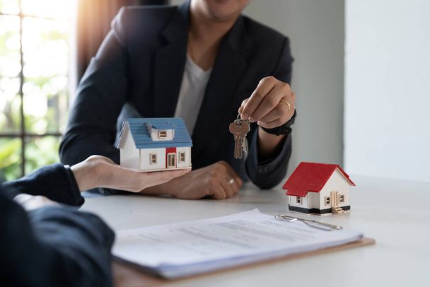 Immobilienmakler verpflichten sich, ein Haus zu kaufen und den Kunden in ihren Agenturbüros Schlüssel zu übergeben. Konzeptvereinbarung. - Foto, Bild
