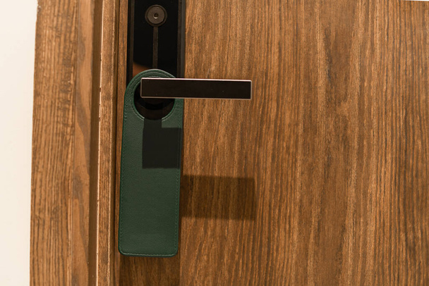 Green door hanger tag on black handle - Photo, Image