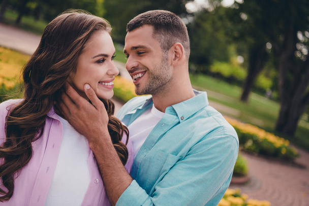 Photo of sweet shiny young wife husband dressed pastel shirts walking kissing enjoying sunshine outdoors backyard. - Foto, imagen