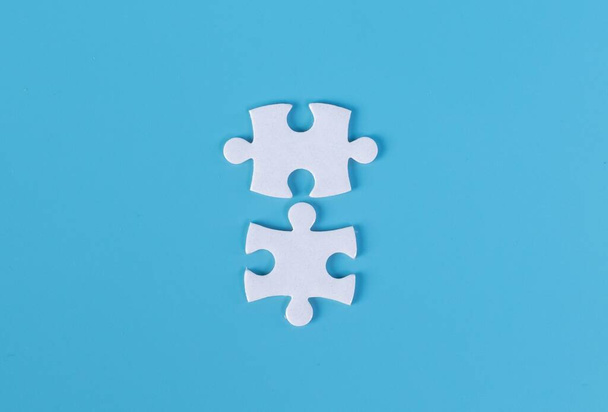 Two pieces of jigsaw puzzle on blue background - Fotografie, Obrázek