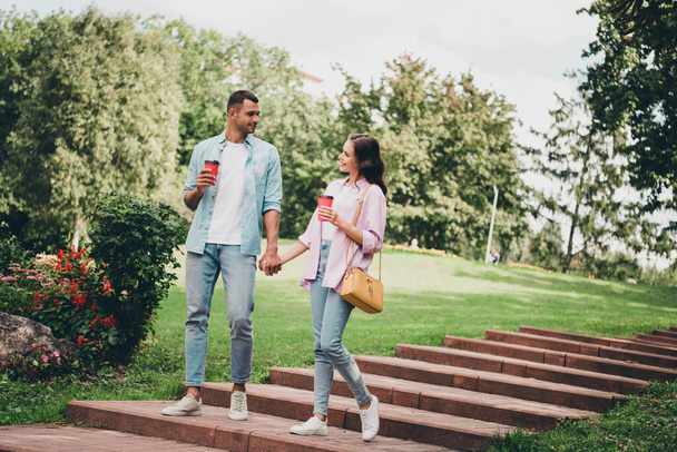 Photo of charming dreamy boyfriend girlfriend wear casual outfits walking stairs drinking beverages enjoying sunny outdoors garden. - Фото, зображення