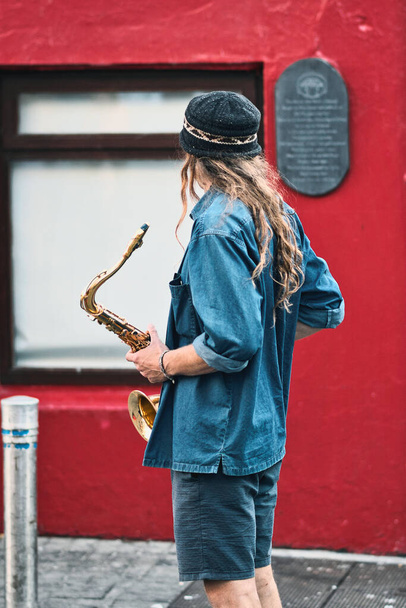Portrait shot of street musician, busker, playing his trumpet during Galway arts Festival in shop street, Ireland  - 写真・画像