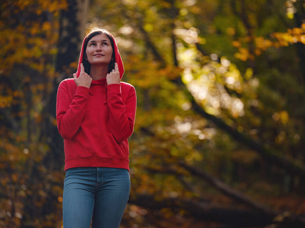 Travel and road trip concept at autumn. Adventure and active lifestyle in nature. Tourist hiking in forest. Asian woman in red hoodie walks in forest. Wanderlust concept. - Foto, imagen
