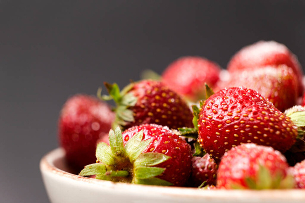 Ripe red strawberries on a plate on a black background, space for text - Fotografie, Obrázek