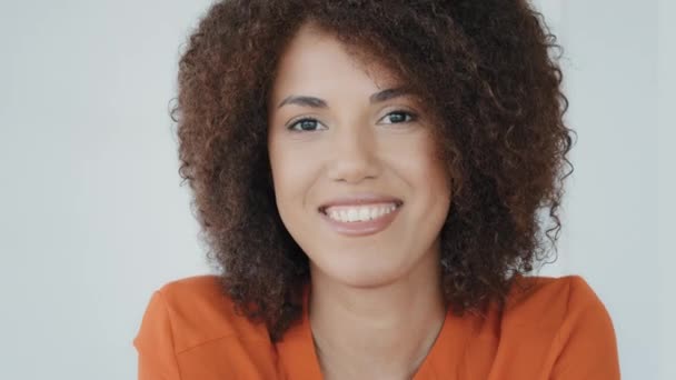 Close-up female face with ideal dark smooth skin. Healthy skincare cosmetic procedures. Satisfied lady client of hairdressing salon with curly hair. Portrait African American girl smiling posing happy - Záběry, video