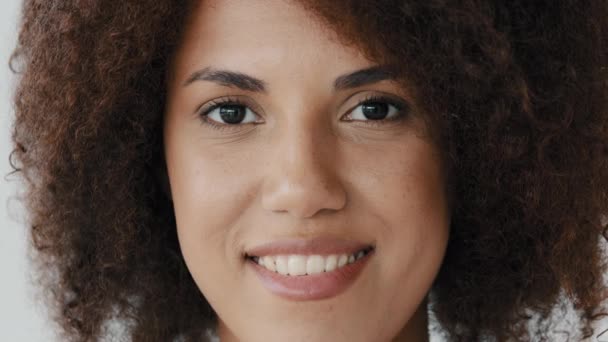 Front view female smiling toothy perfect dark skin natural make-up face. Close up African American curly woman girlfriend biracial lady look at camera open and confident smile with healthy white teeth - 映像、動画