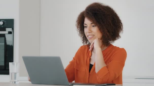 Африканская кудрявая студентка учиться удаленно от дома улыбаясь говорить слушает онлайн удаленной видео-конференц-связи веб-камера с ноутбуком. Бразильская женщина общаться виртуальный чат разговор на домашней кухне - Кадры, видео