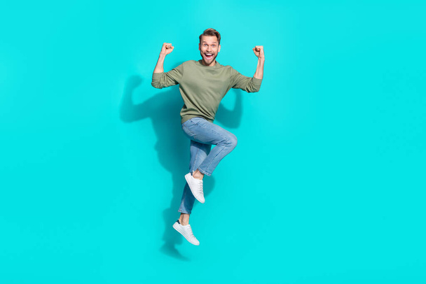 Full length photo of cheerful astonished man jump rejoice win wear pullover isolated blue color background. - Fotoğraf, Görsel