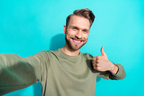Photo of young blond funny guy show thumb up wear khaki pullover isolated on teal color background. - Fotoğraf, Görsel