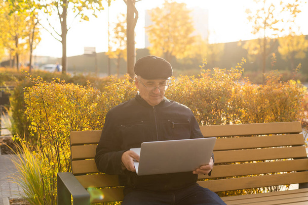 uomo anziano con laptop nel parco autunnale - Foto, immagini