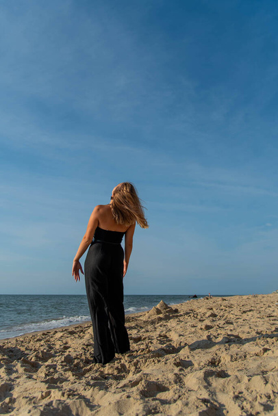 Woman wearing black dress walking on beach. See view - Fotografie, Obrázek