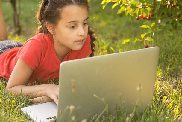 Nauka w domu. Dziewczyna siedzi przy stole z laptopem podczas wideo czatu w szkole z nauczycielem i klasą. Koncepcja kształcenia na odległość. Samoizolacja w kwarantannie - Zdjęcie, obraz