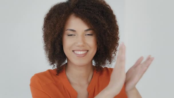 Entusiástica afro-americana mulher interior feliz satisfeito menina biracial com cabelo encaracolado sorrindo palmas mãos olhando para câmera aplaudindo expressa aprovação ovação saudação parabéns gesto - Filmagem, Vídeo