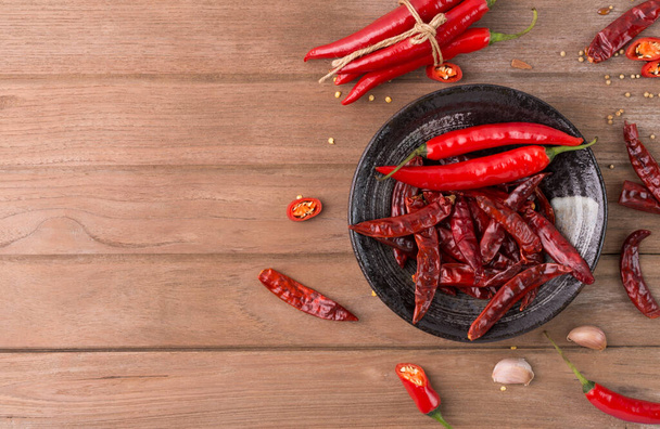 friss piros chili és szárított chili egy csésze fából készült háttér másolási tér felülnézet - Fotó, kép